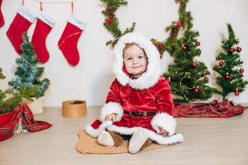 Obraz na płótnie Canvas Little cute boy dressed as Santa near little Christmas trees. Christmas mood