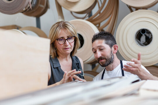 interior designer examining log while standing by coworker at workshop