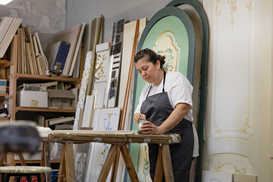 Mature woman painting door while standing at art studio