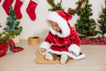 Little cute boy dressed as Santa near little Christmas trees. Christmas mood