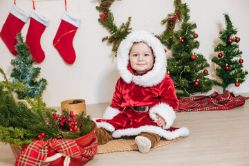 Little cute boy dressed as Santa near little Christmas trees. Christmas mood