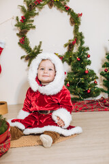 Little cute boy dressed as Santa near little Christmas trees. Christmas mood