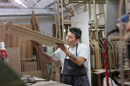 Artist examining wood while standing at workshop