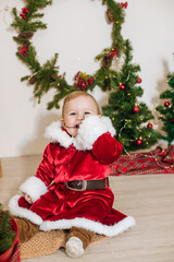 Little cute boy dressed as Santa near little Christmas trees. Christmas mood