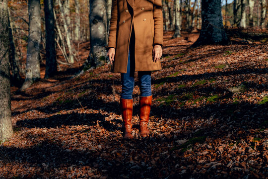 Woman wearing jacket and rubber boot standing on fallen leaf in forest