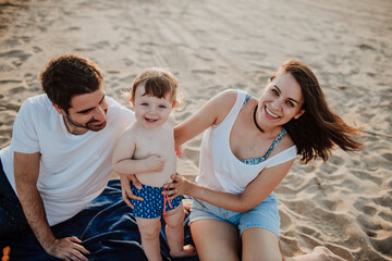 Smiling family with baby boy at beach during sunset