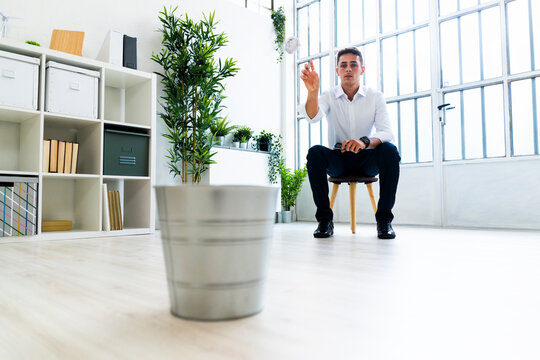 Bored male entrepreneur throwing crumpled paper ball in dustbin at office