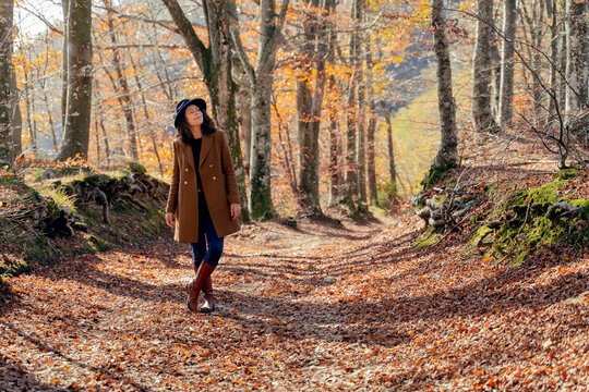 Mature woman wearing jacket standing with eyes closed on footpath in forest
