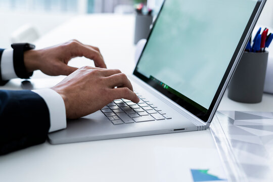 Hands of male professional tying on laptop keyboard at desk in workplace