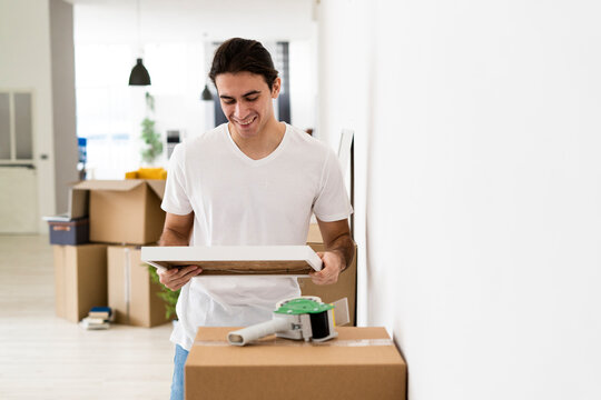 Smiling man looking at picture frame while reliving memories at new apartment