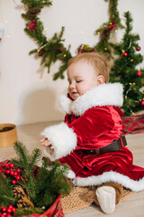 Little cute boy dressed as Santa near little Christmas trees. Christmas mood