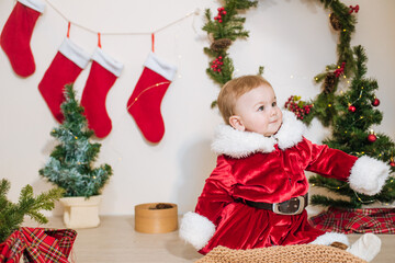 Little cute boy dressed as Santa near little Christmas trees. Christmas mood