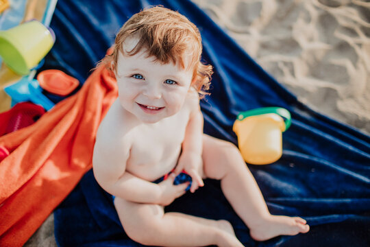 Cute boy smiling while playing at beach on sunny day