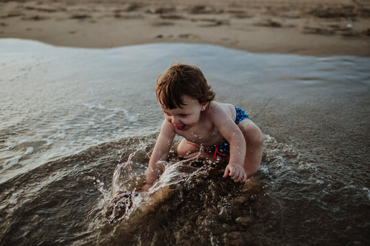 Baby boy playing in water at beach during sunset
