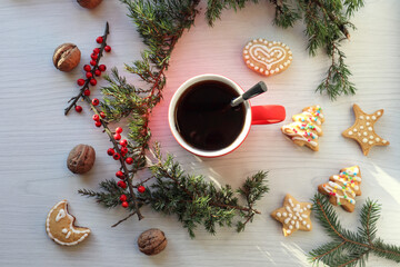 Obraz na płótnie Canvas Homemade holiday cookies with a red Cup of tea on the background of juniper branches, white background, top view-the concept of a pleasant hassle of preparing a holiday with your family