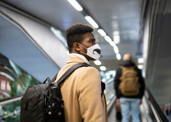Young man wearing face mask standing on escalator at station