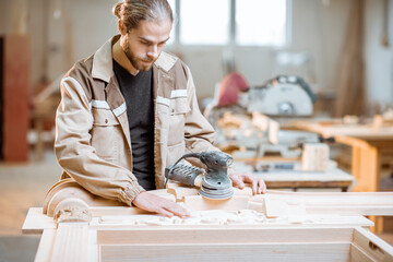 Handsome carpenter checks out carving quality of a joiner's product at the carpentry manufacturing