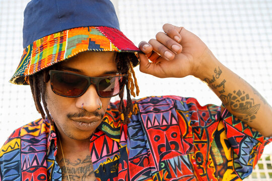 Young man wearing sunglasses and hat standing outdoors