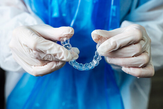 Doctor holding transparent dental aligner while standing at clinic