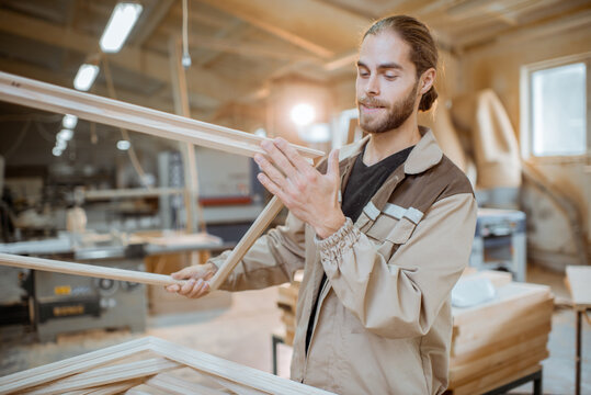 Handsome carpenter checking the quality of the window frame before the paint at the carpentry workshop