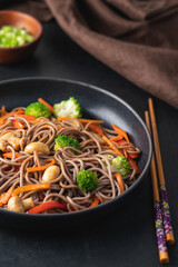 Vegan Stir fry with vegetables and mushrooms  in black bowl. Close up view. Black slate background
