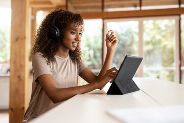 Businesswoman wearing headphones using digital tablet while sitting at home