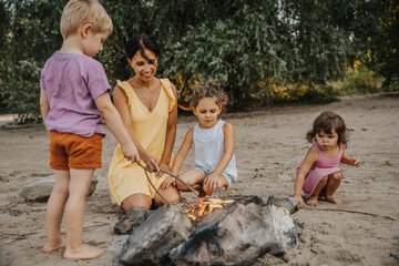 Mature woman and children making barbecue at beach