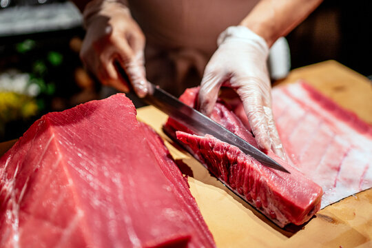 Male chef cutting raw seafood into slices at restaurant