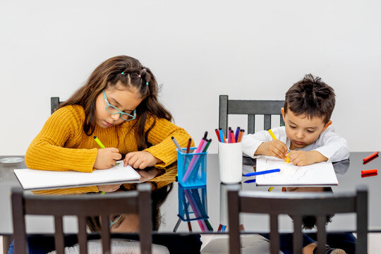 Brother and sister learning drawing while sitting in living room