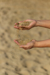 Woman's arm playing with the sand in her hands.
