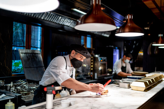 Chefs wearing protective face mask preparing food in kitchen