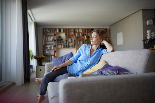 Woman with head in hands resting while sitting on sofa at home