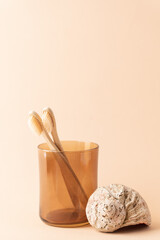 Minimalistic lifestyle concept. Natural bamboo brushes in  brown glass and shell on beige background