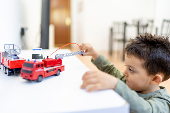 Boy playing with fire engine toy at home