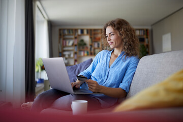 Smiling woman doing online shopping on laptop at home