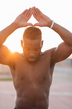 Young man meditating while standing at park during sunset