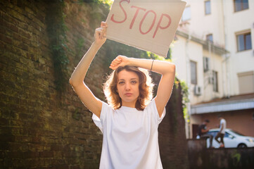Young protesting woman in white shirt and jeans holds protest sign broadsheet placard with slogan...