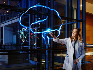Female neurologist analyzing brain with light painting at hospital