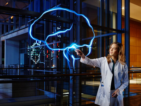 Female neurologist analyzing brain with light painting at hospital