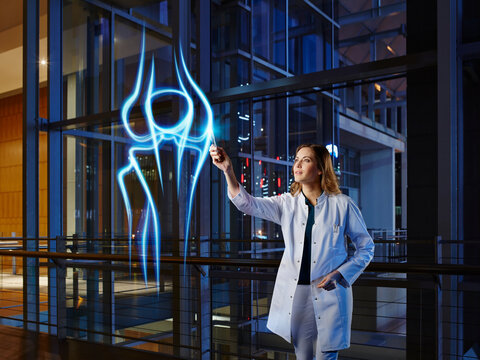 Female orthopedist analyzing knee joint in laboratory at hospital