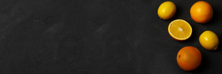 Oranges and lemons banner on dark surface with space for text. Top view.