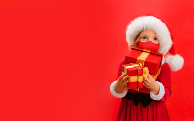 Funny child in Santa red hat and face mask holding Christmas gift in hand.