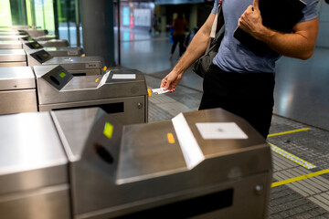 Man holding ticket at turnstile in subway