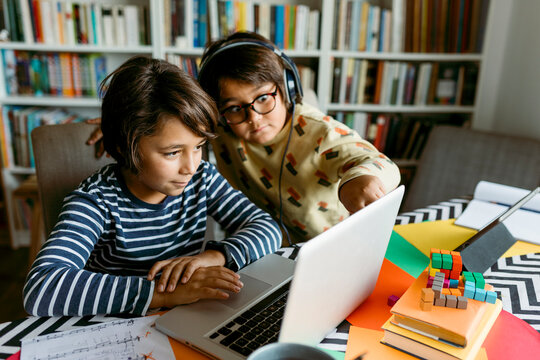 Boys looking at laptop while e-learning in living room