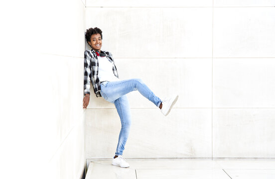 Playful young female hipster standing against white wall