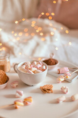 Homemade hot delicious chocolate or aromatic cocoa drinks with marshmallows in a mug on a white table.
