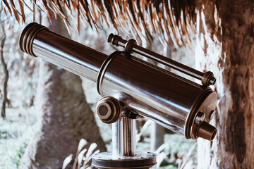 Closeup shot of a city telescope under a tree