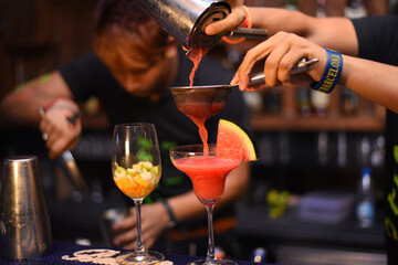 barman pouring alcohol cocktail in martini glasses for christmas party