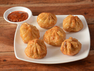 Veg fried momo with sauce served over a rustic wooden background, selective focus