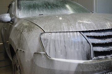 The car body is covered with soap suds to remove dirt. Car wash